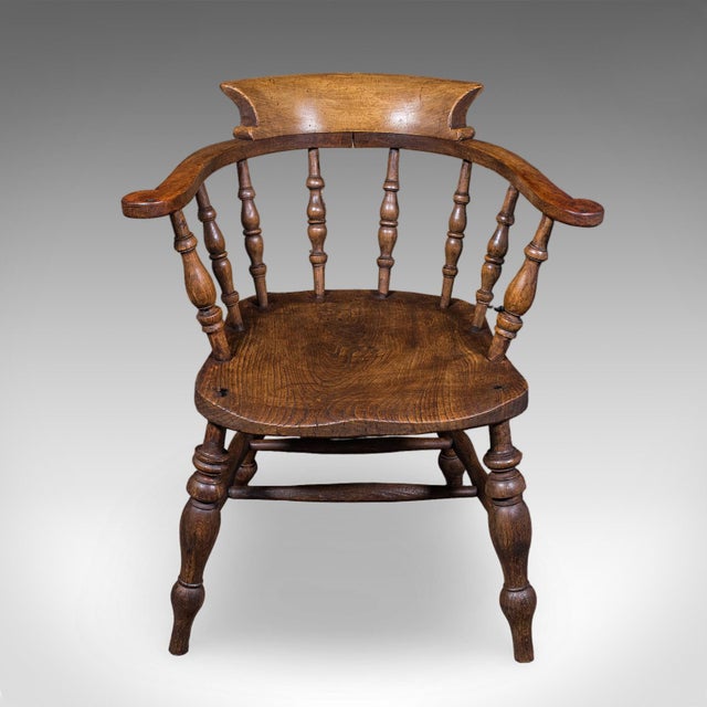 This is an antique smoker's bow chair. An English, elm and beech country house elbow seat, dating to the Edwardian period,...