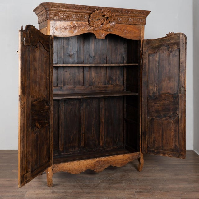 18th century French two door wedding armoire, crafted in pine with a rich brown patina. Elaborate carving is seen...