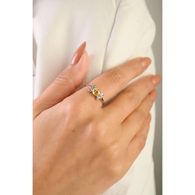 This elegant cluster ring showcases one vibrant oval-cut yellow sapphire totaling 0.73 carats, set in 14k white gold. The...