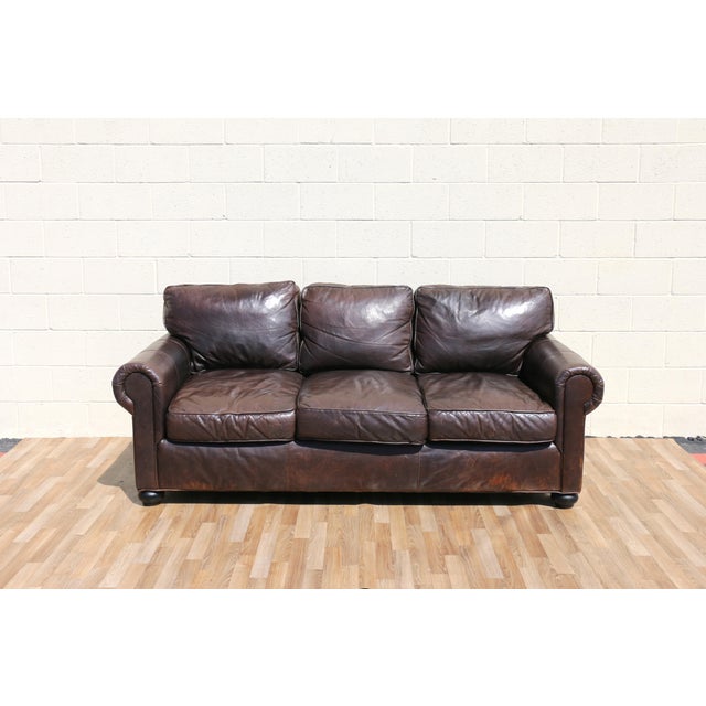A timeless three-seat leather sofa by Restoration Hardware, upholstered in rich brown leather with a beautifully aged...