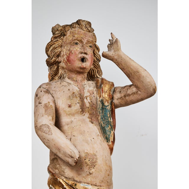 An iconic, hand carved, gessoed, painted, and parcel-gilt, Italian polychrome sculpture of tousle curled angel in...