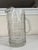 This vintage Anchor Hocking mid-century water pitcher features a bold, geometric grid cut-glass pattern that reflects...