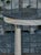 A French Empire style bleached wood side table from the 19th century with black marble top, three column legs, in-curving...