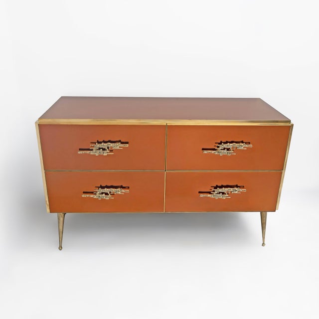 An elegant chest of drawers featuring surfaces entirely clad in amber-toned mirror, creating a sophisticated interplay of...