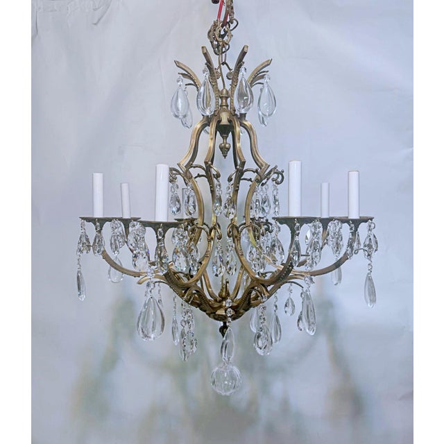This grand eight‑arm chandelier features an ornate brass or bronze frame with beautifully curved arms and intricate...