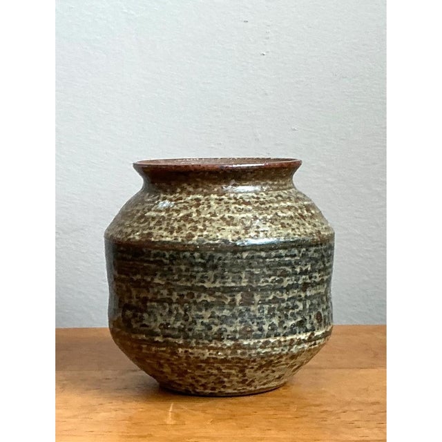 This stoneware vase embraces a squat, rounded silhouette, its full body swelling generously outward before drawing inward...