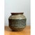 This stoneware vase embraces a squat, rounded silhouette, its full body swelling generously outward before drawing inward...