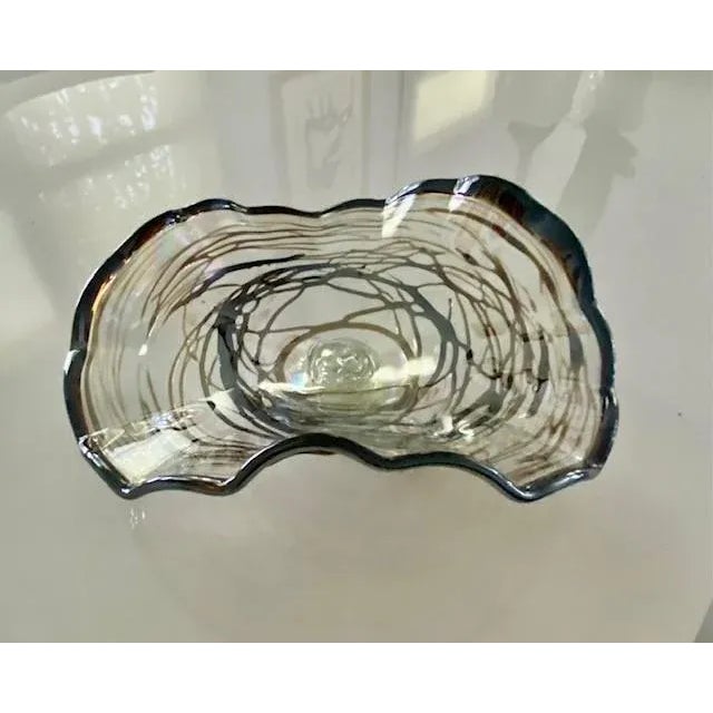 This fanciful glass bowl is decorative or functional to serve fruit or candy on a coffee table. It has an asymmetrical...