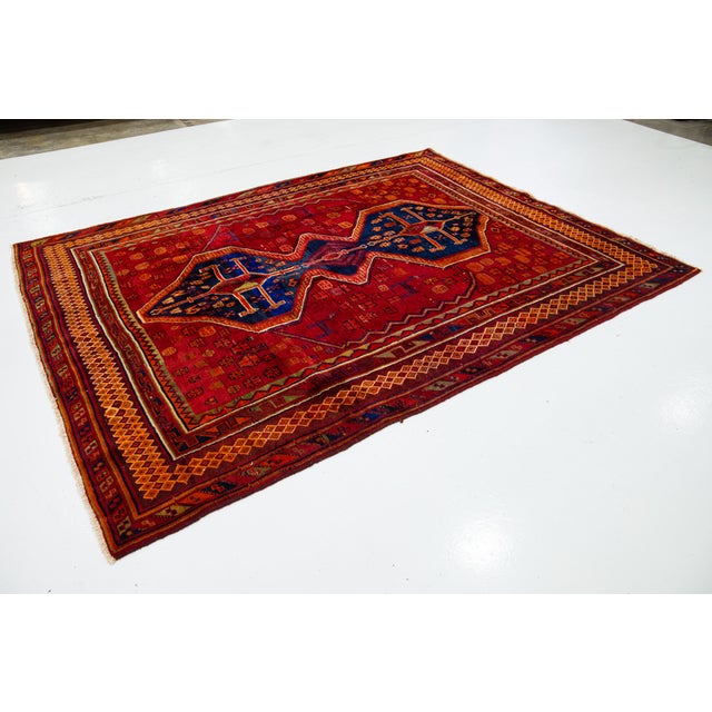 Vintage Hand-knotted Persian Shiraz Wool rug. This rug has a red field and navy blue accents in an over-tribal motif. this...