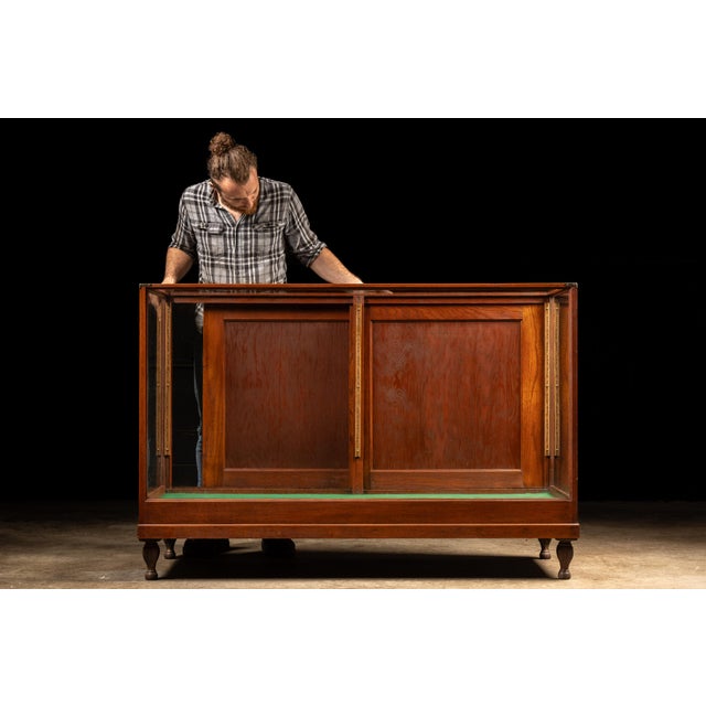 Antique commercial display cabinet constructed from solid wood and fitted with large glass viewing panels. The substantial...