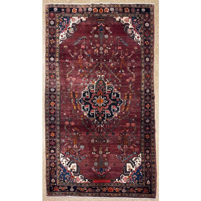 Antique hand-knotted rug from the Nahavand region of western Iran, featuring a rich, abrashed burgundy field with a large,...