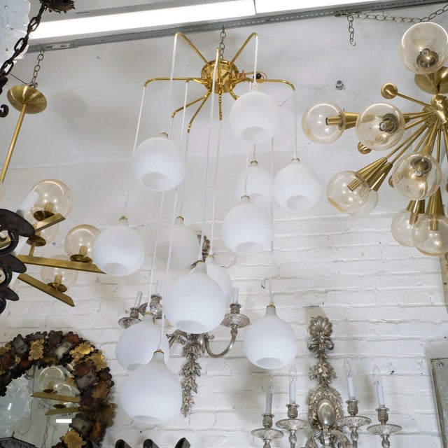 Large brass chandelier composed of suspended frosted glass bulb-form shades.