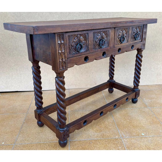 Early 20th century walnut console table with slab top on a frieze with two drawer fronts decorated with carved and incised...