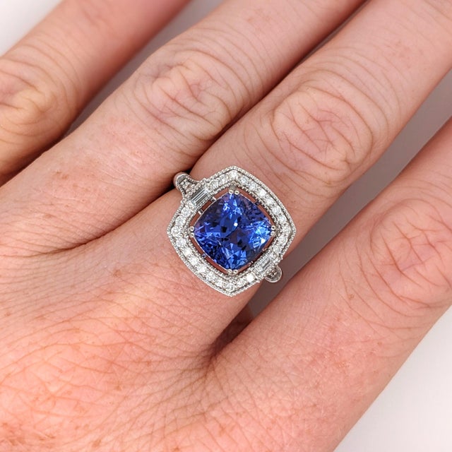A tanzanite glows in a deep violet-blue at the heart of this solid 14K white gold ring, flanked by thirty-two earth-mined...
