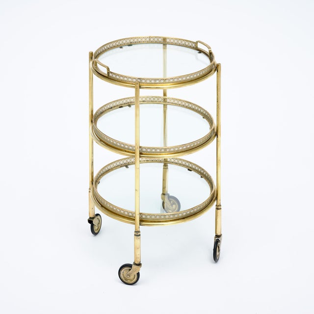 Brass bar cart from the Art Deco period in France. This petite table has three glass shelves, the top of which has handles...