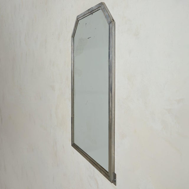 An Italian wall mirror from the 1960s, framed in brushed metal with subtle variations of silver and bronze tones. The...