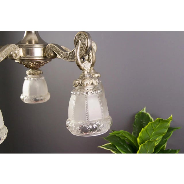 Art Deco style bronze chandelier with floral and foliate motifs on arms, stem and canopy. Five bronze arms, each with...