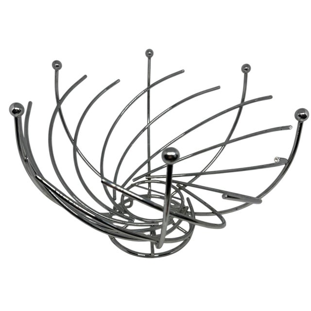 Postmodern, spiral-shaped metal fruit bowl basket with a dynamic open-wire design. Curved stainless-steel wires fan out...