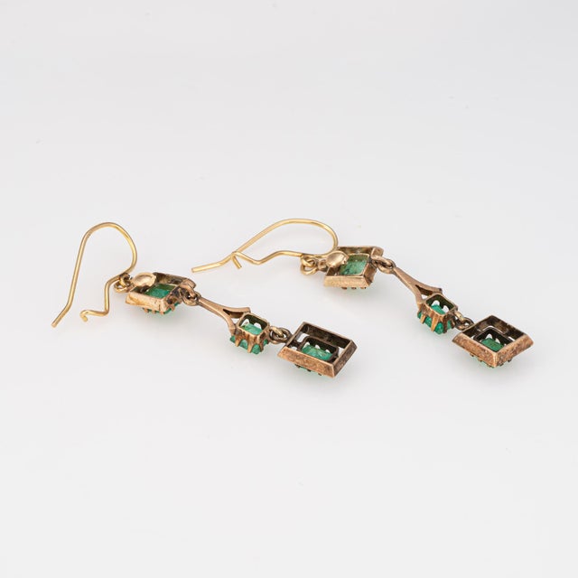 Stylish emerald drop earrings crafted in 14k yellow gold (circa 1960s). Emeralds graduate in size measuring from 4.5mm,...
