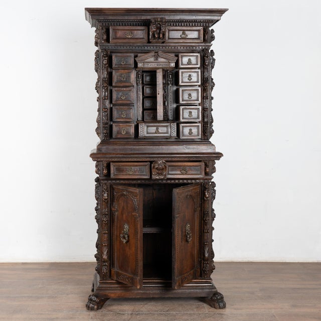 Heavily carved baroque walnut cabinet with putti, faces, flourishes and more. Top has two exterior drawers, middle section...