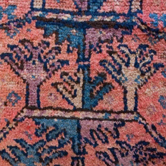 An early 20th century Balochi carpet with three narrow tree of life panels on an orange background, surrounded by a...