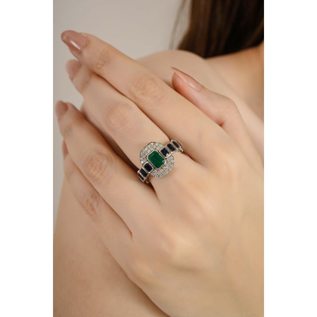 This Art Deco Inspired ring features a vibrant emerald cut emerald at the center, and blue sapphire weighing 2.34 carats,...