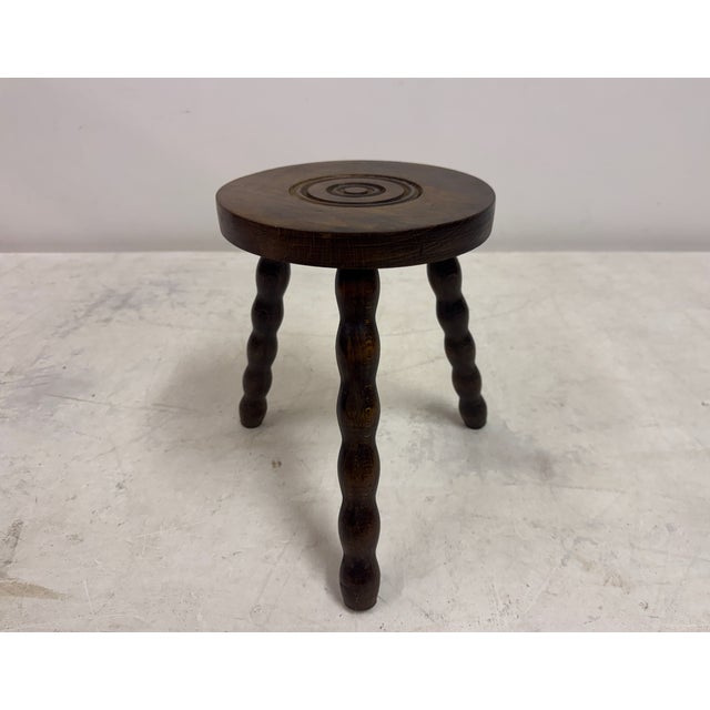 Vintage tripod stool Three turned bobbin-style legs Round wood top featuring a concentric circle (bullseye or target)...