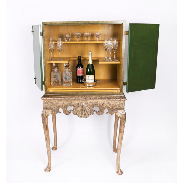 A fabulous polychromed Green lacquered and gilt japanned cocktail cabinet-on-stand, retailed by Harrods and bearing their...