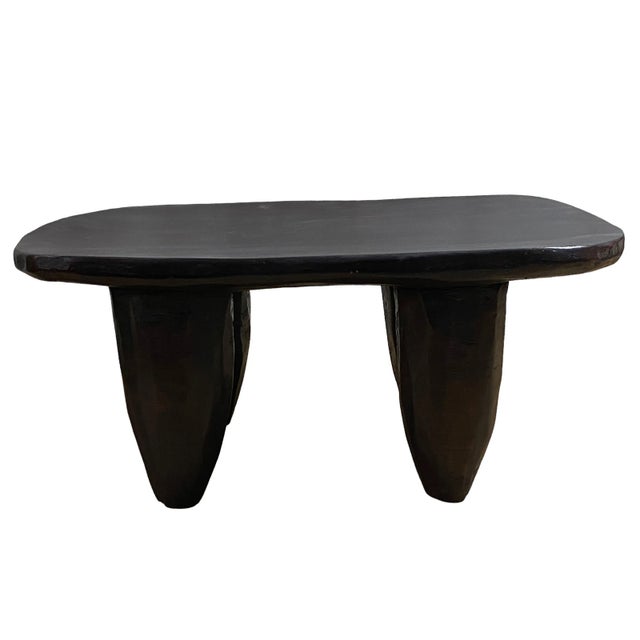 An impressive African Senufo milk stool, boasting four tapered legs and an abstract shape crafted from a single piece of...