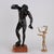 Bronze sculpture depicting a faun with cymbals on a red marble base. This piece is attributed to the mentioned...