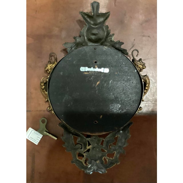 Ornate Victorian Art Nouveau with gilded and cast metal accents. Features a decorative bird at the top and a sunburst or...