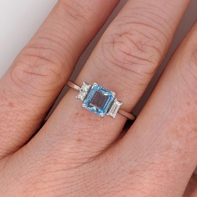 An aquamarine takes centre stage in a clear sea-blue at the centre of this solid 14K white gold ring, encircled by three...