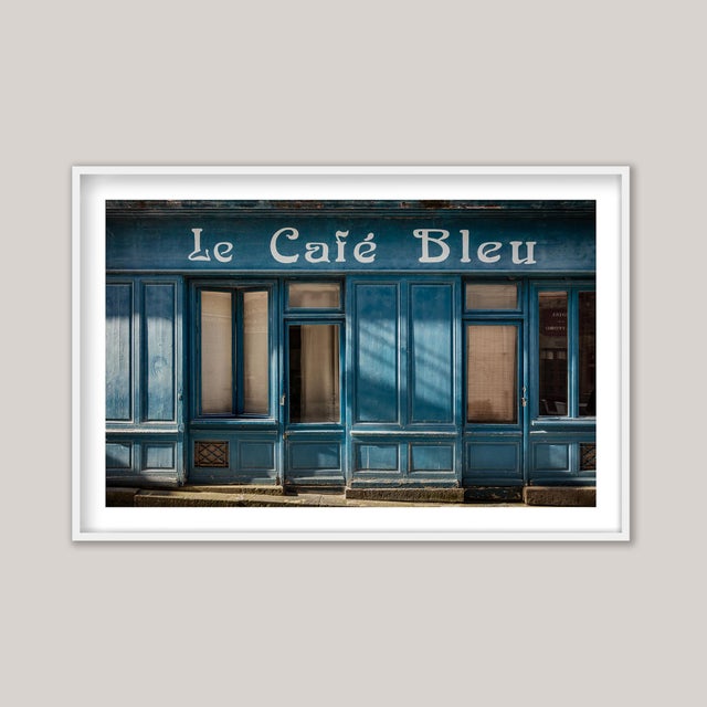 A photograph captures the facade of a charming vintage café in northwestern France - Le Café Bleu. Now closed and left...