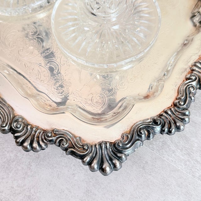 A generously sized silver plate tray by FB Rogers Silverware with a dramatic scalloped, rococo-style rim featuring raised...