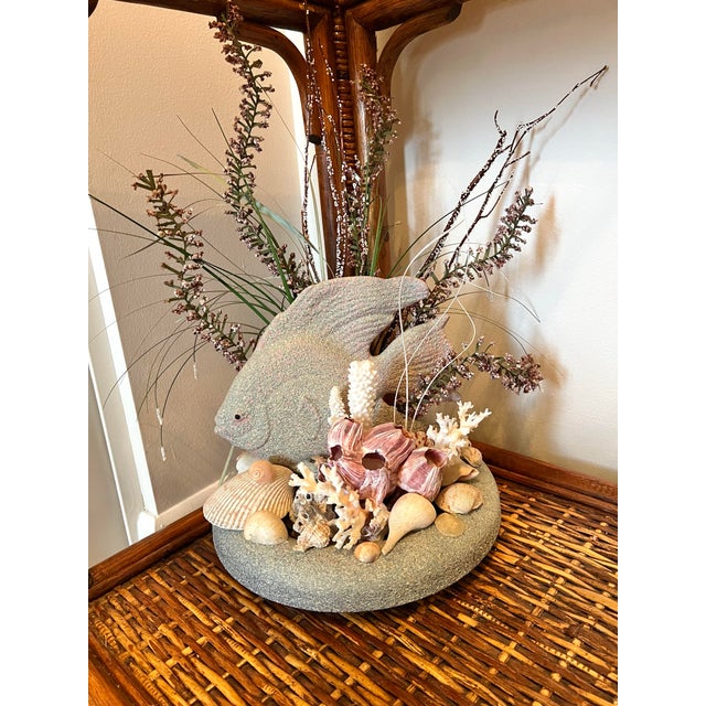 This is an ocean-themed decorative floral centerpiece featuring a stone-style fish figurine surrounded by various...
