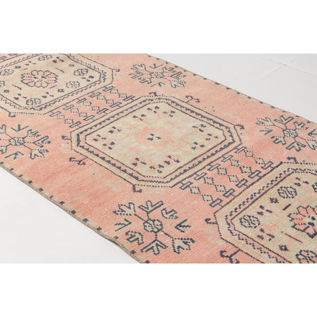 This is a vintage Turkish Oushak rug from the Mid 20th Century. The piece was hand-knotted.