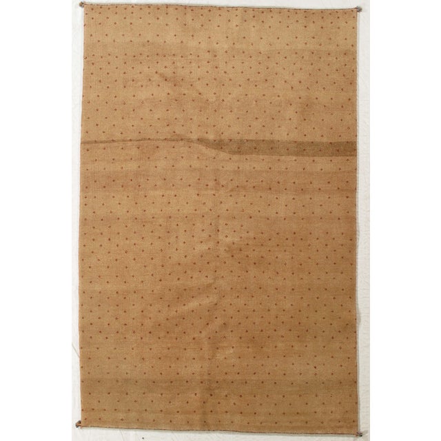 Vintage hand-knotted Persian Gabbeh rug featuring a warm, golden-beige field with scattered small geometric motifs...