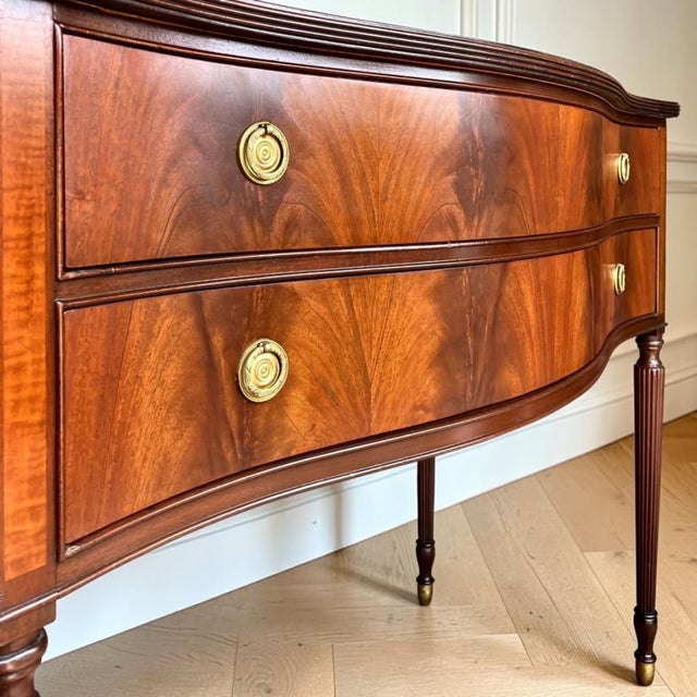 This 1930s Federal Sheraton-style server showcases stunning book-matched flame mahogany, a graceful bow front, fluted legs...
