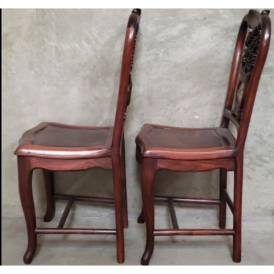 A beautifully crafted pair of Chinese hardwood side chairs, likely rosewood, featuring graceful horseshoe backs, hand-...