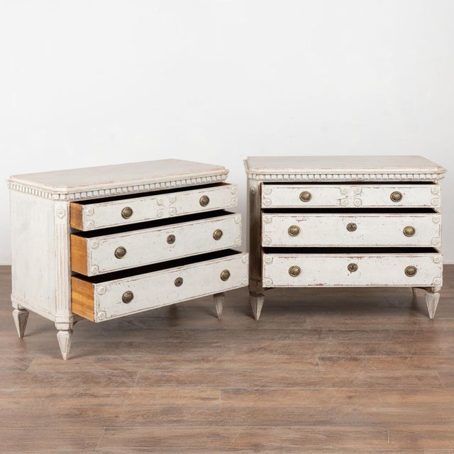 A pair of Gustavian pine chest of drawers painted in shades of antique white and soft gray, fitting their Swedish origin....