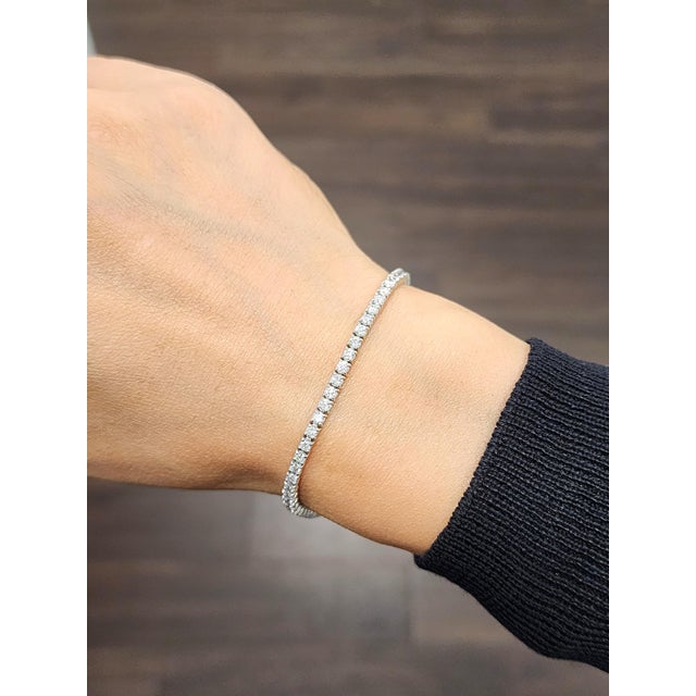 This refined tennis bracelet embodies modern sophistication. Featuring a continuous line of 64 natural round-cut white...