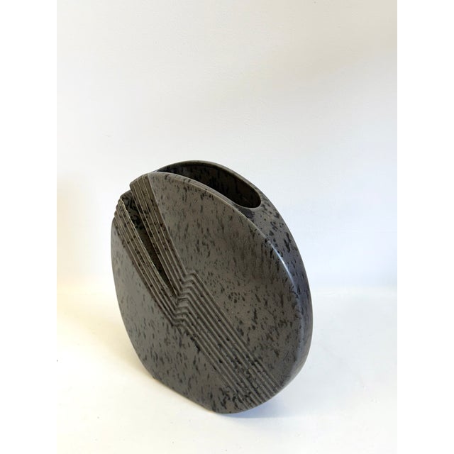 This dark gray ceramic vase by Nereo Boaretto from 1972 has a unique lenticular shape with a narrow opening and a deep,...