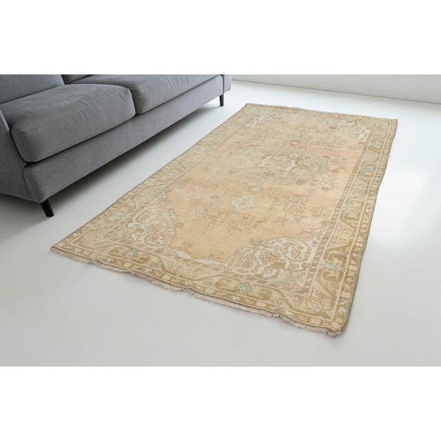 This is a vintage Turkish Oushak rug from the Mid 20th Century. The piece was hand-knotted.