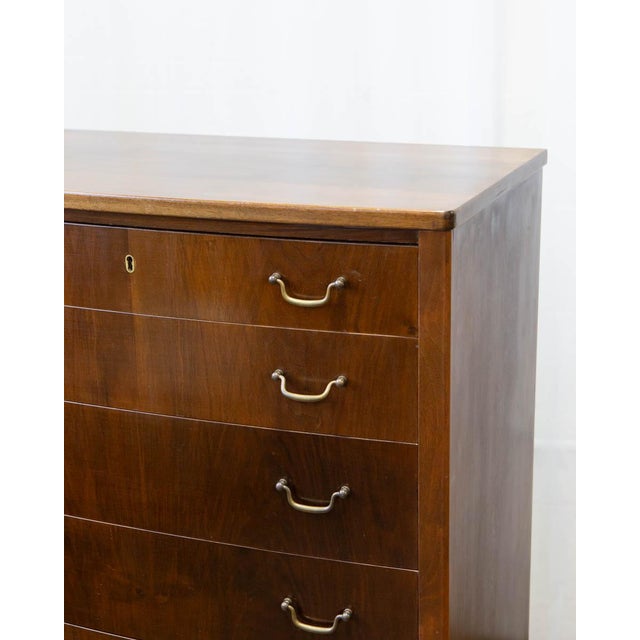A tall Danish walnut chest of drawers in the Wanscher style, produced in the 1950s. Six graduated drawers run from deep at...