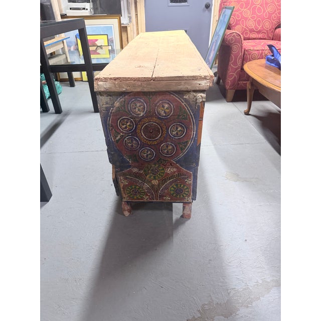 Striking hand-painted wooden storage chest featuring intricate folk-art motifs in rich shades of blue, red, green, and...