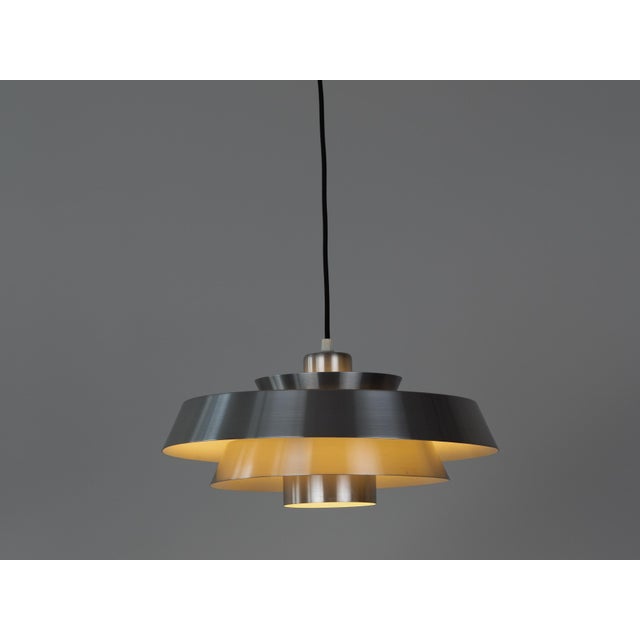 The aluminum Nova lamp, designed by Jo Hammerborg in 1963. When lit, the lamp provides a soft, glare-free downward glow,...