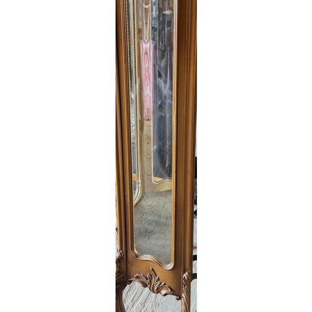 This vintage French Rococo–style curio cabinet features a tall, slender silhouette with ornate carved details, glass side...