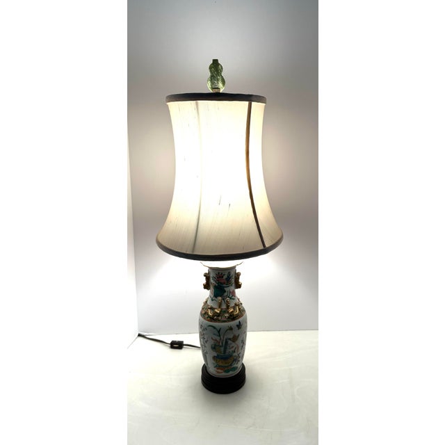 19th Century Chines famille porcelain table lamp. Floral motifs with chi-long handles. Measures 26” h x 4” x 5” Measures...
