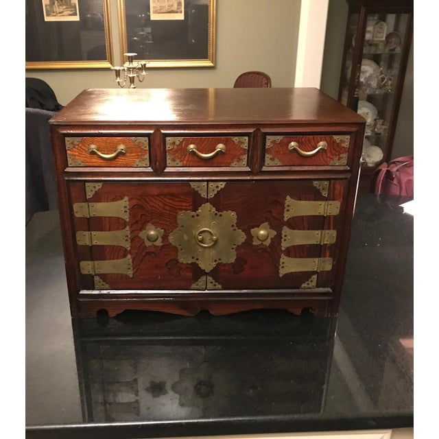 A Korean hardwood diminutive chest with brass mounts. The two doors open to reveal storage and drawers with three drawers...