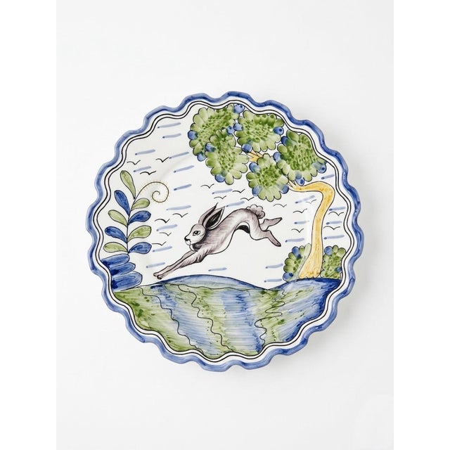 This charming set of four decorative plates features a lively, hand-painted scene of a leaping hare mid-stride across a...